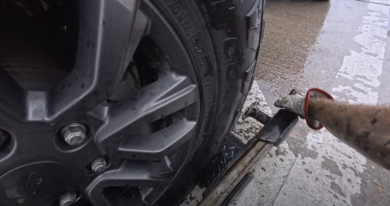 Roadside assistance technician changing flat tire for stranded driver in Babylon, NY